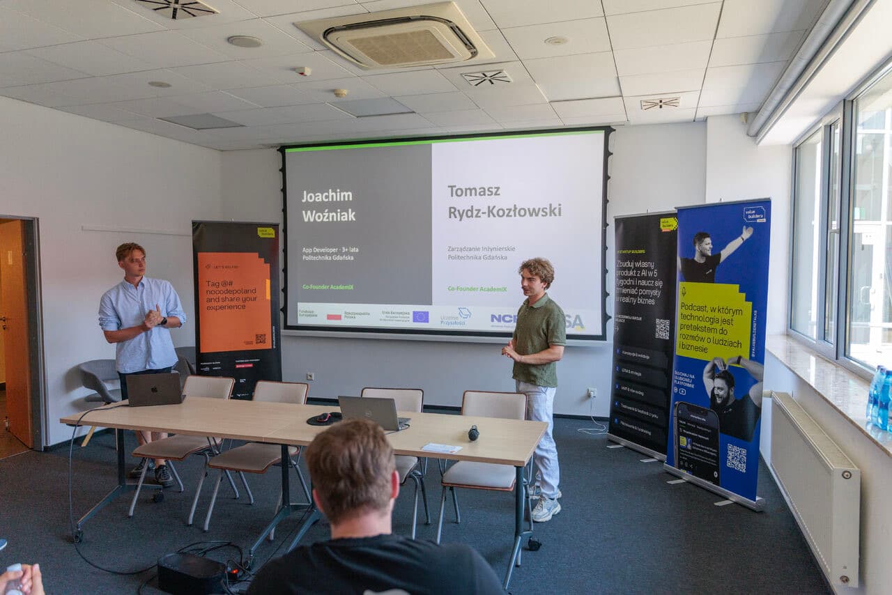 Joachim i Tomasz z AcademiX prezentują projekt na Demo Day, na ekranie za nimi slajd z ich nazwiskami i rolami